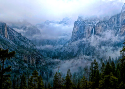 Misty mountains and dense forest under a cloudy sky.