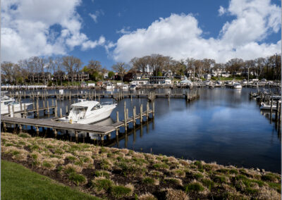 A calm lakeside scene with boats docked and houses in the background.