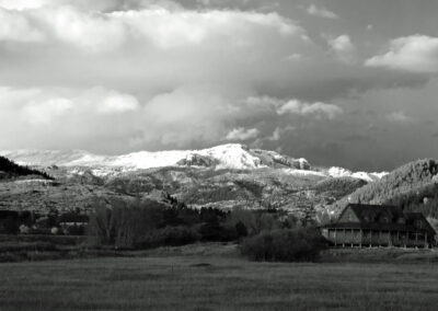 Snow-covered mountain under a cloudy sky with houses in the foreground.