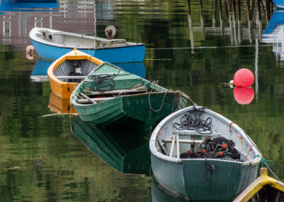Three colorful boats floating peacefully on calm water at a dock.