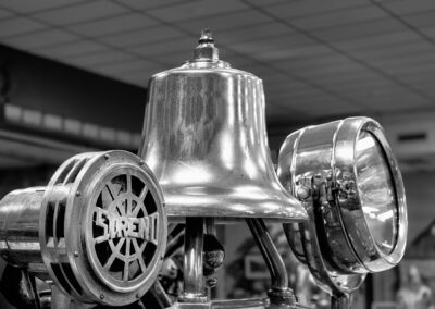 A shiny bell surrounded by vintage metal objects in black and white.