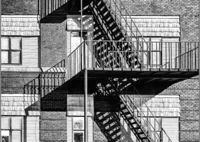 Black and white photo of a fire escape on a brick building.