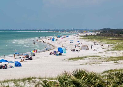 A sunny beach with people relaxing under umbrellas and tents.