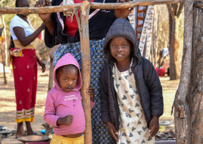 Two children posing with a wooden swing outdoors during the day.
