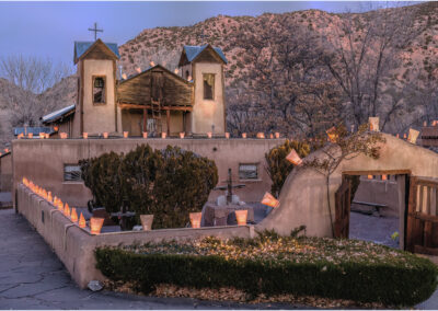 A historic mission church at dusk with glowing lanterns.