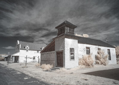 Old wooden building under a cloudy sky in a desolate area.