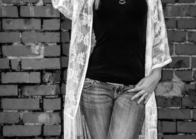 Woman in casual outfit posing against a brick wall.