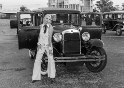 Person in 1970s attire posing with a vintage car.