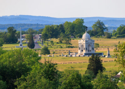Historic white chapel in a green countryside landscape with distant mountains.