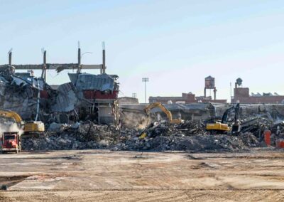 Demolition site with heavy machinery clearing rubble from a large building.