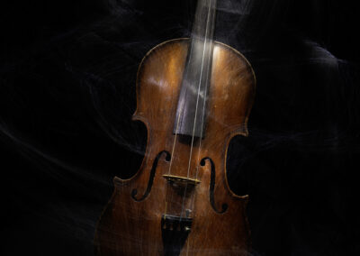 A violin illuminated against a dark, smoky background.