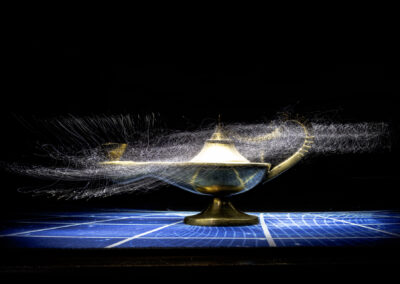 A golden genie lamp with magical smoke swirling around it on a blue grid surface.