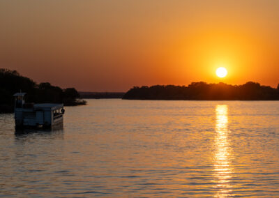 Sunset over a calm river with a boat on the left side.