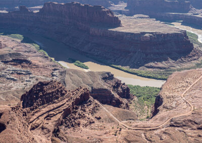 A winding river flows through a deep canyon with rugged red rock formations.