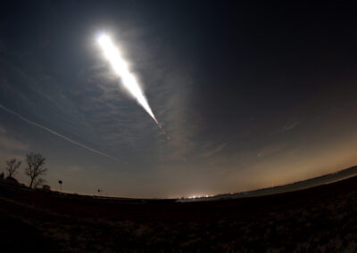 A rocket launching into the night sky with a bright trail.