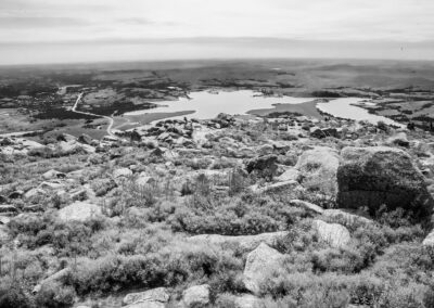 Black and white landscape of rocky terrain overlooking a lake.