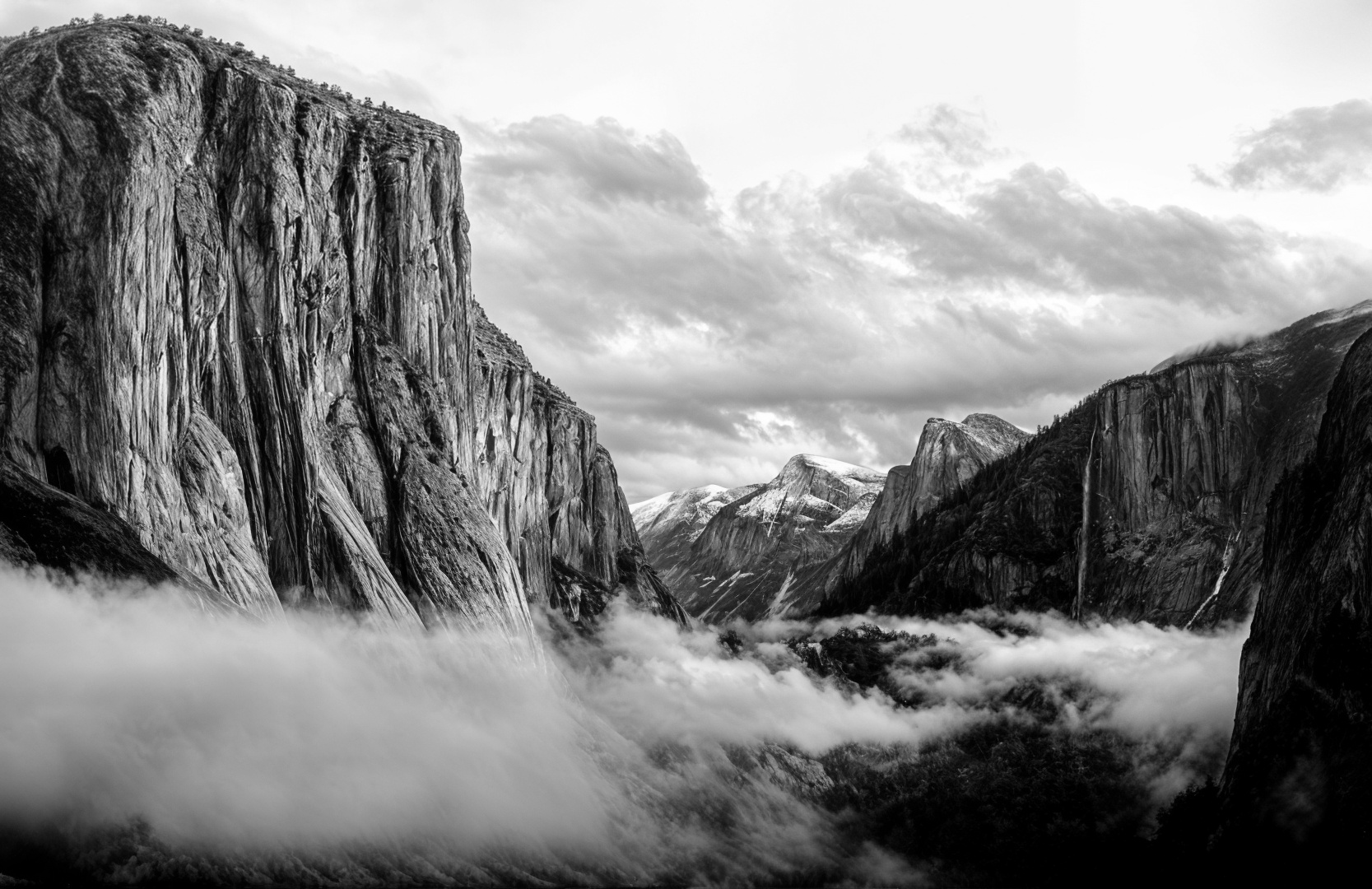 Black and white photo of a mountainous landscape with clouds.