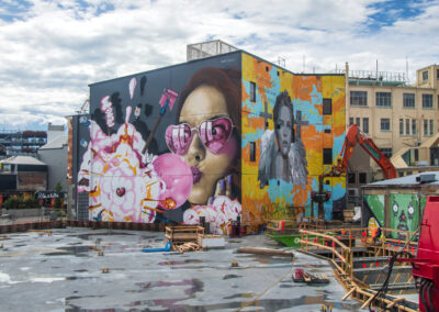 Colorful street art murals on urban building walls under a cloudy sky.