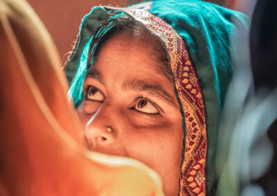 Close-up of a woman with a turquoise headscarf looking upward.