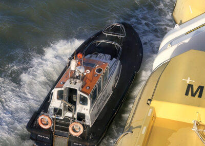 A small pilot boat navigating near a larger yellow ship.