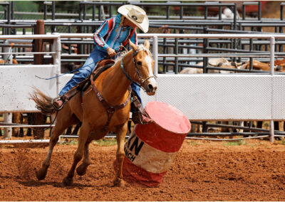 Cowboy on horseback navigating a barrel in a rodeo event.