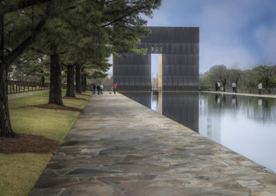 Memorial structure with reflecting pool surrounded by trees and visitors.