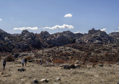 Hikers exploring a rocky, arid landscape under a clear blue sky.