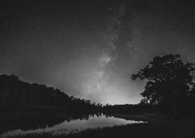 Stars and the Milky Way shining over a calm lake at night.