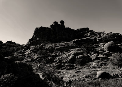 Black and white photo of a rocky hill with unique rock formations on top.