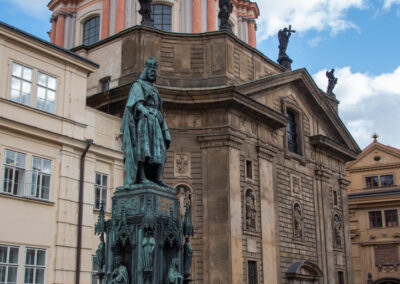 Statue in front of a historic building with a green dome under a blue sky.